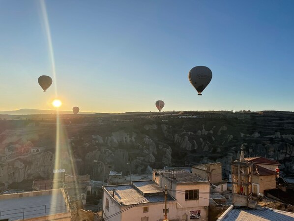 A view of a town with buildings and hot air balloons in the sky.