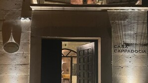A building entrance with a large rock formation in the background and a door labeled "CASA CAPPADOCIA". - Casa Cappadocia (Ürgüp)