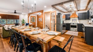 Een moderne keuken met houten balken, een eethoek met een lange tafel en uitzicht op de omgeving.