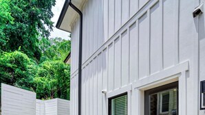 Ein modernes Haus mit weißer Fassade, einem Ziegeluntergrund und einem Betonweg, der zum Eingang führt.