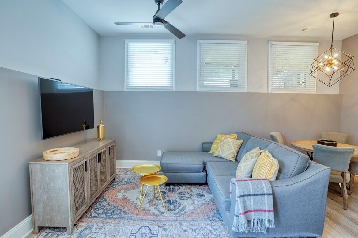 Una sala de estar moderna con un sofá gris, un televisor de pantalla plana, un mueble de madera y una alfombra estampada.