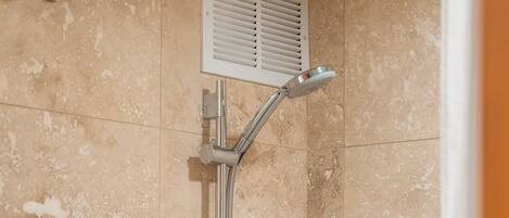A shower with a handheld showerhead and a wall-mounted control panel.