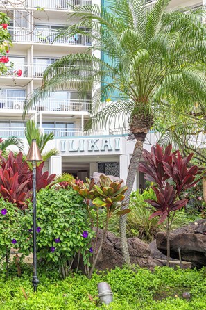 Ett hotell med en skylt som visar texten ”ILIKAI”, omgivet av frodig grönska och en palm.