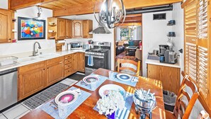 Une cuisine avec des meubles de rangement en bois, une table à manger dressée avec des assiettes, un four à micro-ondes et une cuisinière.