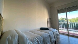 Une chambre avec un lit, une fenêtre donnant sur un paysage verdoyant et un balcon avec une balustrade.