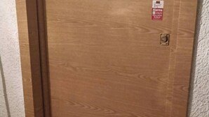 Une porte en bois avec une poignée argentée et un petit autocollant rouge sur le côté droit.