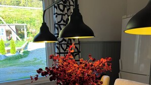 Un tavolo da pranzo con un vaso di fiori rossi, una parete a motivi bianchi e neri e due lampade a sospensione nere.
