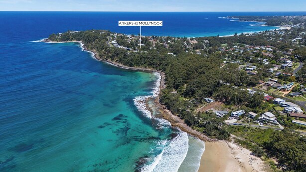 An aerial view of a coastal area with a beach, clear blue waters, and a mix of residential and natural landscapes. - Ankers Home at Mollymook (Mollymook Beach)