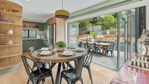 A dining area with a round table, chairs, and a chessboard. - Ankers Home at Mollymook (Mollymook Beach)
