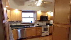 Una cocina compacta con armarios de madera, lavavajillas, estufa y microondas.