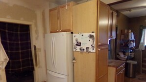 Cocina compacta con muebles de madera, un refrigerador blanco y una pequeña encimera.