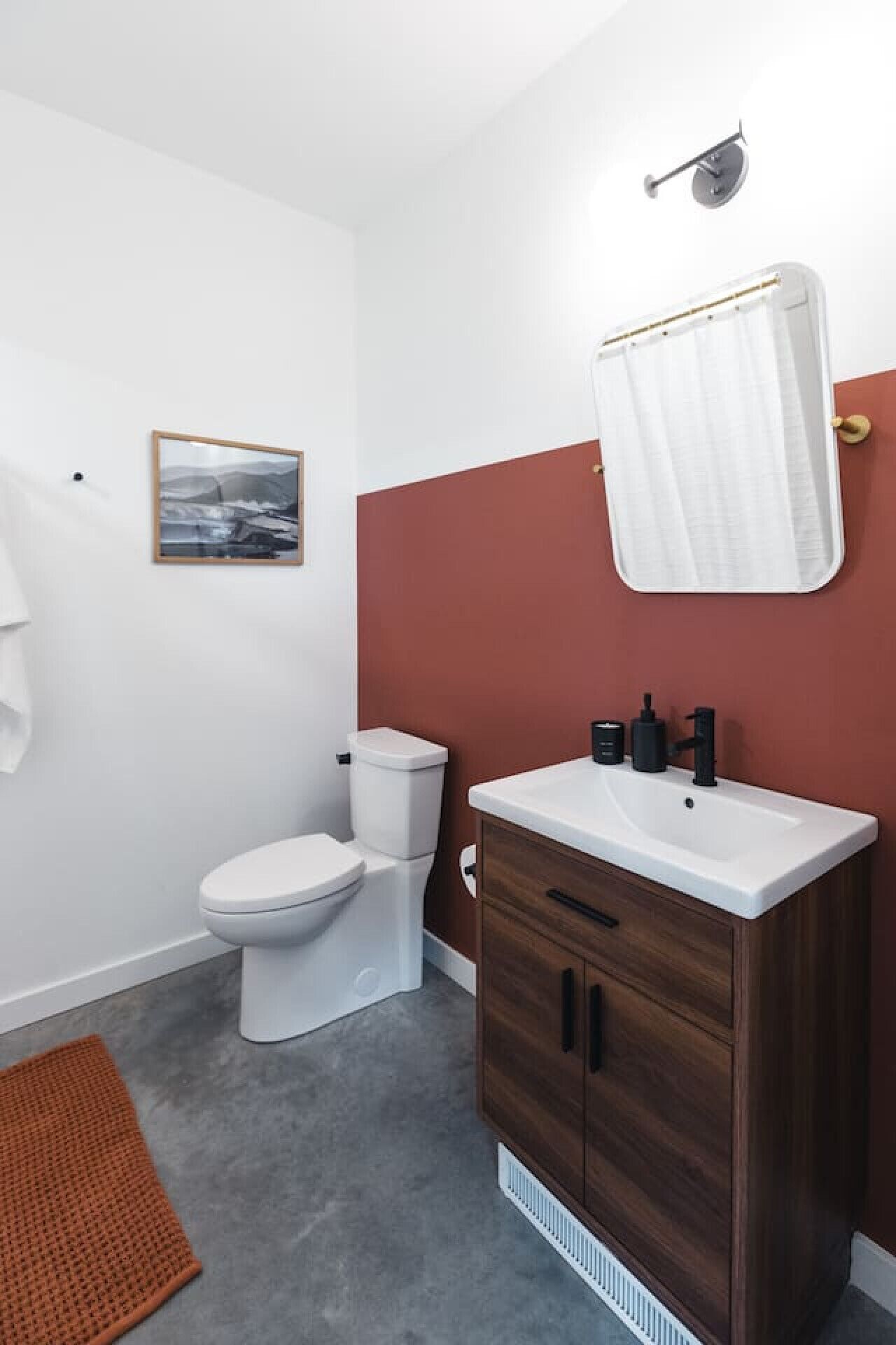 Une salle de bain moderne avec des toilettes blanches, un meuble-lavabo en bois et un espace douche.