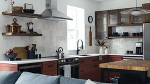 A modern kitchen with wooden cabinets, a stainless steel stove, and a wooden dining table. - Modern 2 bedroom apartment located in a building built in 1896 (Kaslo)