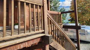 A wooden deck with a railing, a brick wall, and a parked camper. - Modern 2 bedroom apartment located in a building built in 1896 (Kaslo)