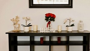 A reception desk with a 'Welcome' sign, potted plants, candles, and a framed picture on the wall.