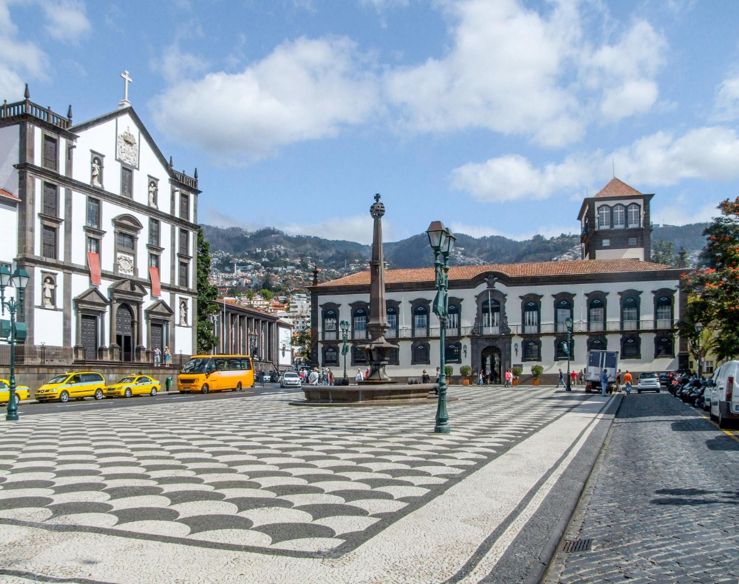 A historic square with cobblestone pavement, a prominent church, and a bell tower.