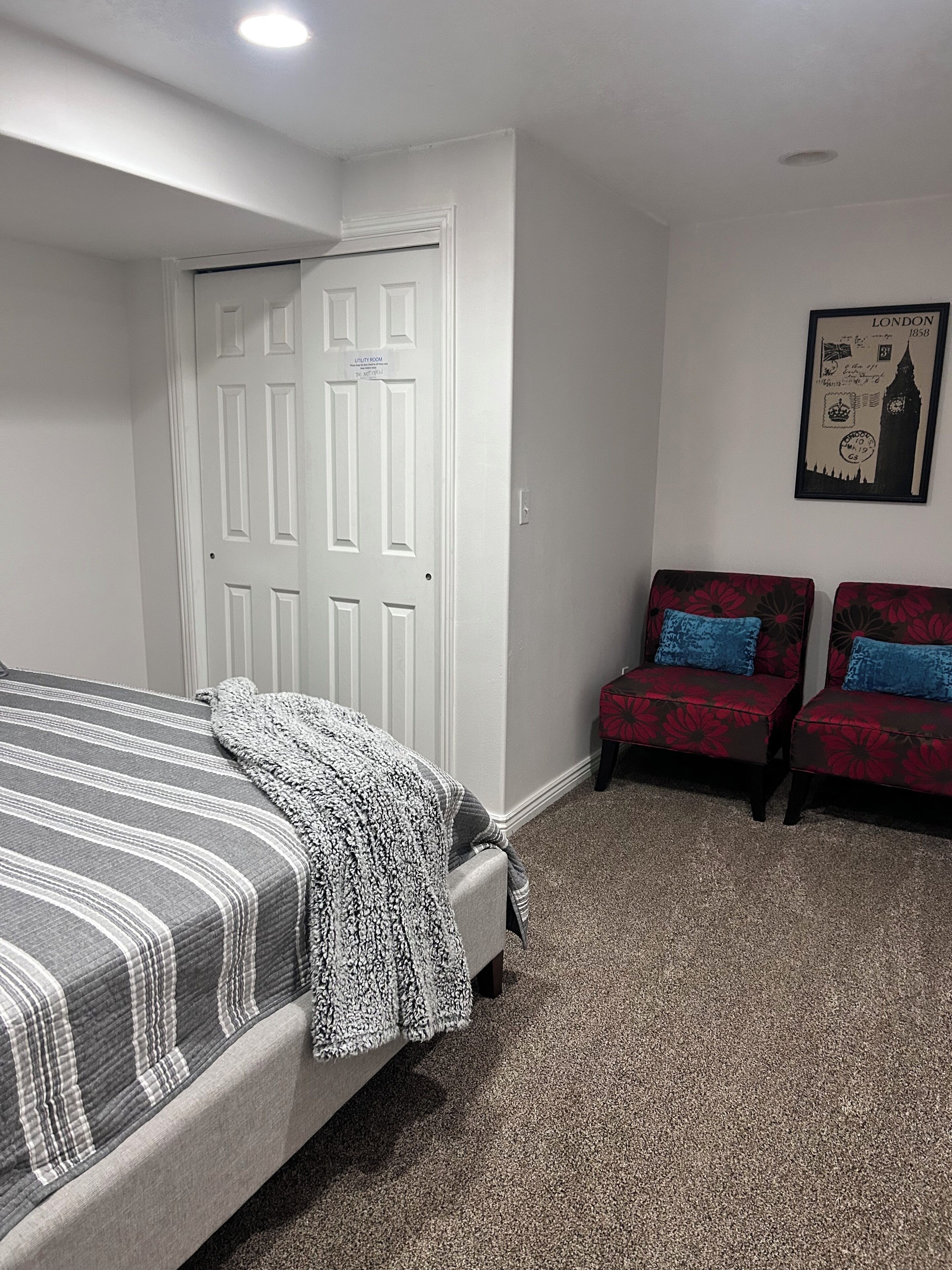 Une chambre à coucher avec un lit, une porte et deux fauteuils.