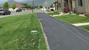 A residential street with houses, a clear sky, and mountains in the background.