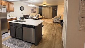 A modern kitchen with a central island, wooden cabinets, and a built-in dishwasher.