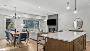 Una cocina moderna con una isla grande, comedor y sala de estar con chimenea.