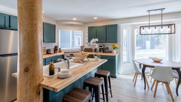 A modern kitchen with a wooden island, stainless steel appliances, and teal cabinetry. - Cute modern 2 bed retreat, a perfect basecamp for your adventures! (Fraser)