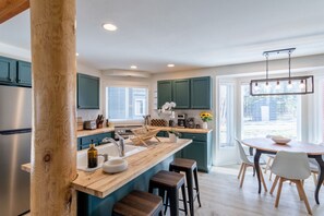 Una cucina moderna con un'isola in legno, elettrodomestici in acciaio inossidabile e mobili color petrolio.
