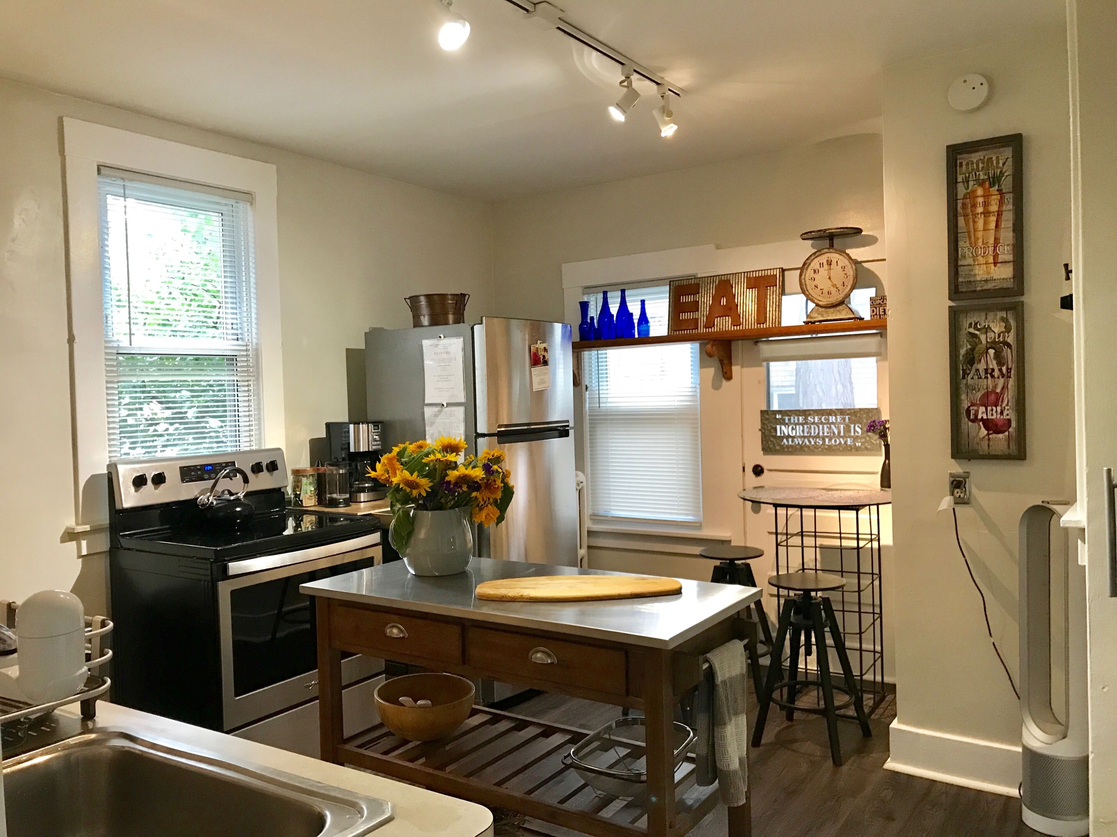 A modern kitchen with stainless steel appliances, a wooden island, and a clock on the wall.
