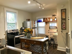 A modern kitchen with stainless steel appliances, a wooden island, and a clock on the wall.