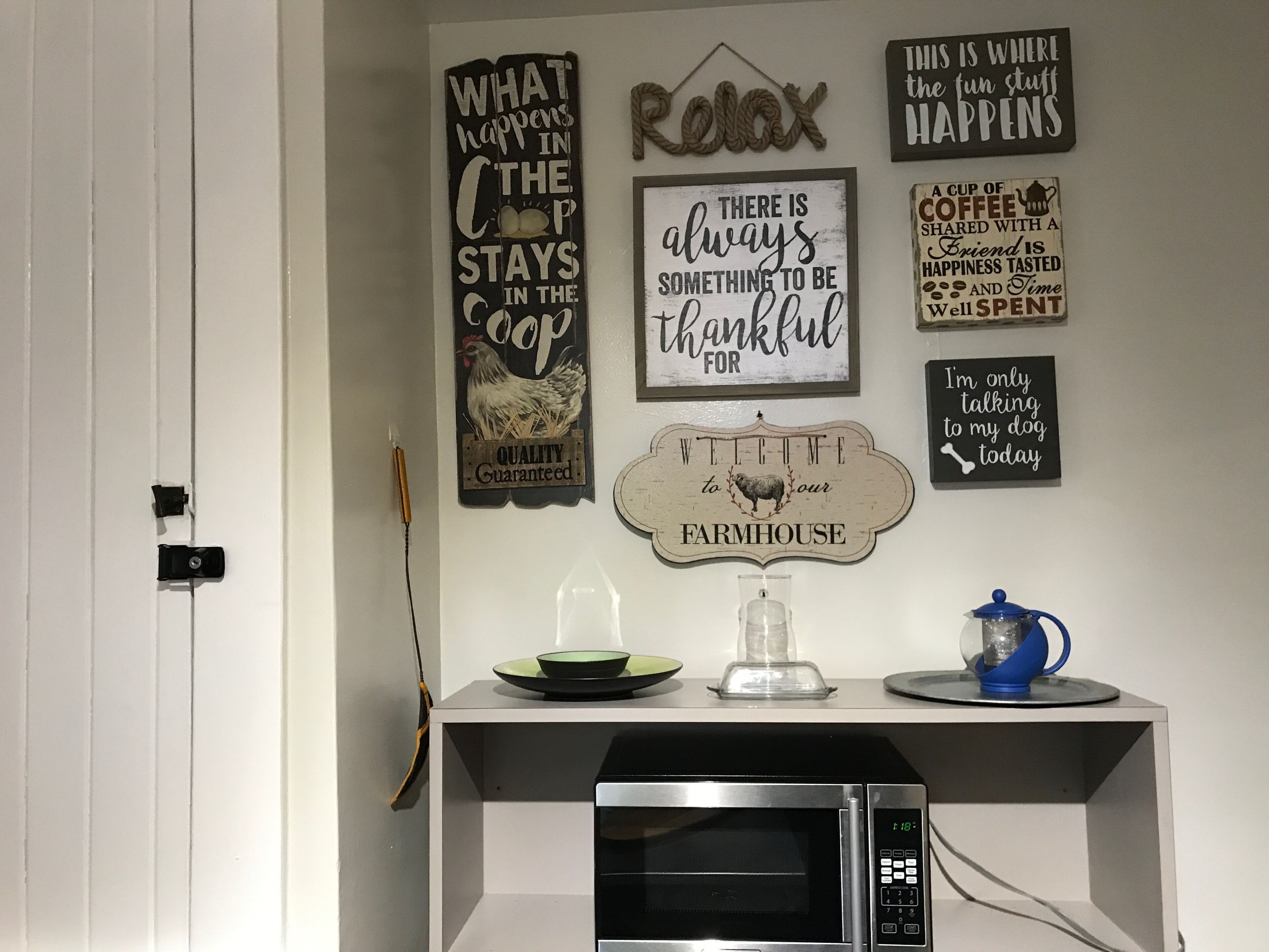 Un coin cuisine équipé d’un four à micro-ondes, d’une machine à café et agrémenté de différents panneaux décoratifs accrochés au mur.