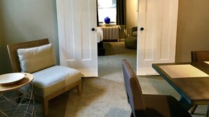 A room with a sliding door, a sofa, a small round table, and a dining table.
