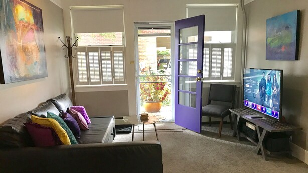 A living room with a sofa, a television, and a door leading outside.