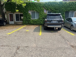 A parking lot with two cars, one SUV and one sedan, parked in designated spaces.