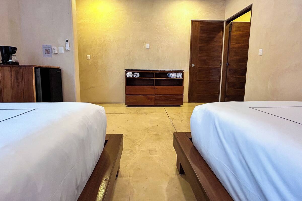 A room with two beds, a wooden dresser, and a wardrobe.