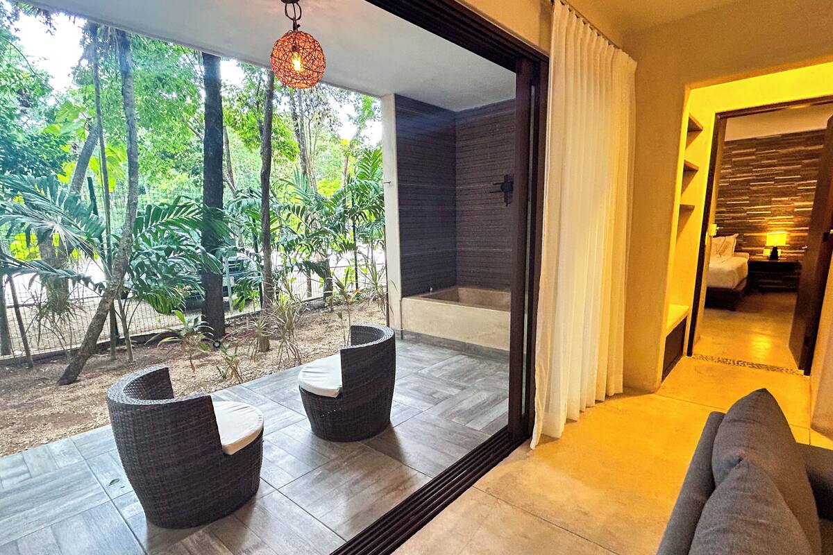 A modern room with a large window, a bathtub, and a sofa.