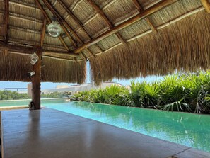 A pool area with a thatched roof, surrounded by lush greenery. - Albra Tulum  (Tulum)
