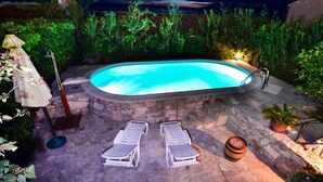 En pool med två solstolar och en bar i tropisk stil.