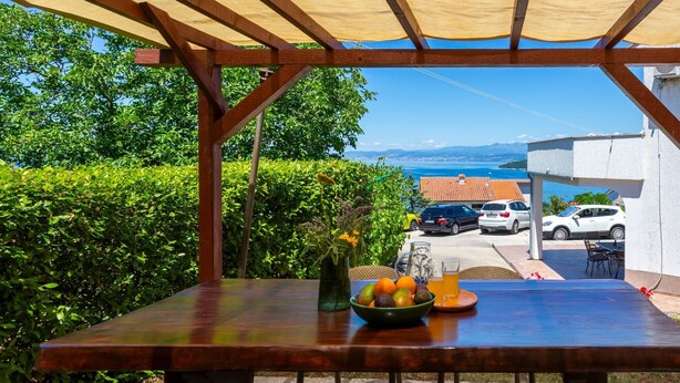 Ein Sitzbereich im Freien mit Tisch, Stühlen und Blick auf das Meer.