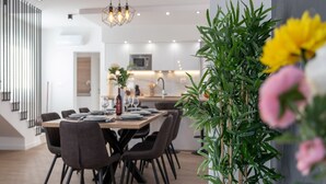 A modern dining area with a long table, chairs, and a hanging light fixture.