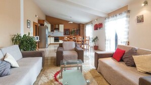 A spacious living area with a sofa, a glass coffee table, and a dining area with chairs and a table.