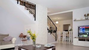 En moderne stue med trappe, sofa, sofabord og spiseplads.