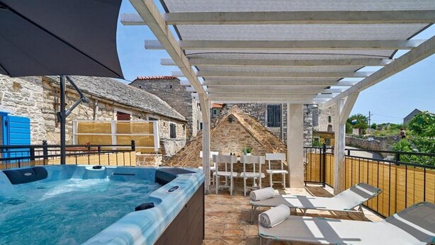 Een bubbelbadgedeelte met lounge stoelen en een pergola.