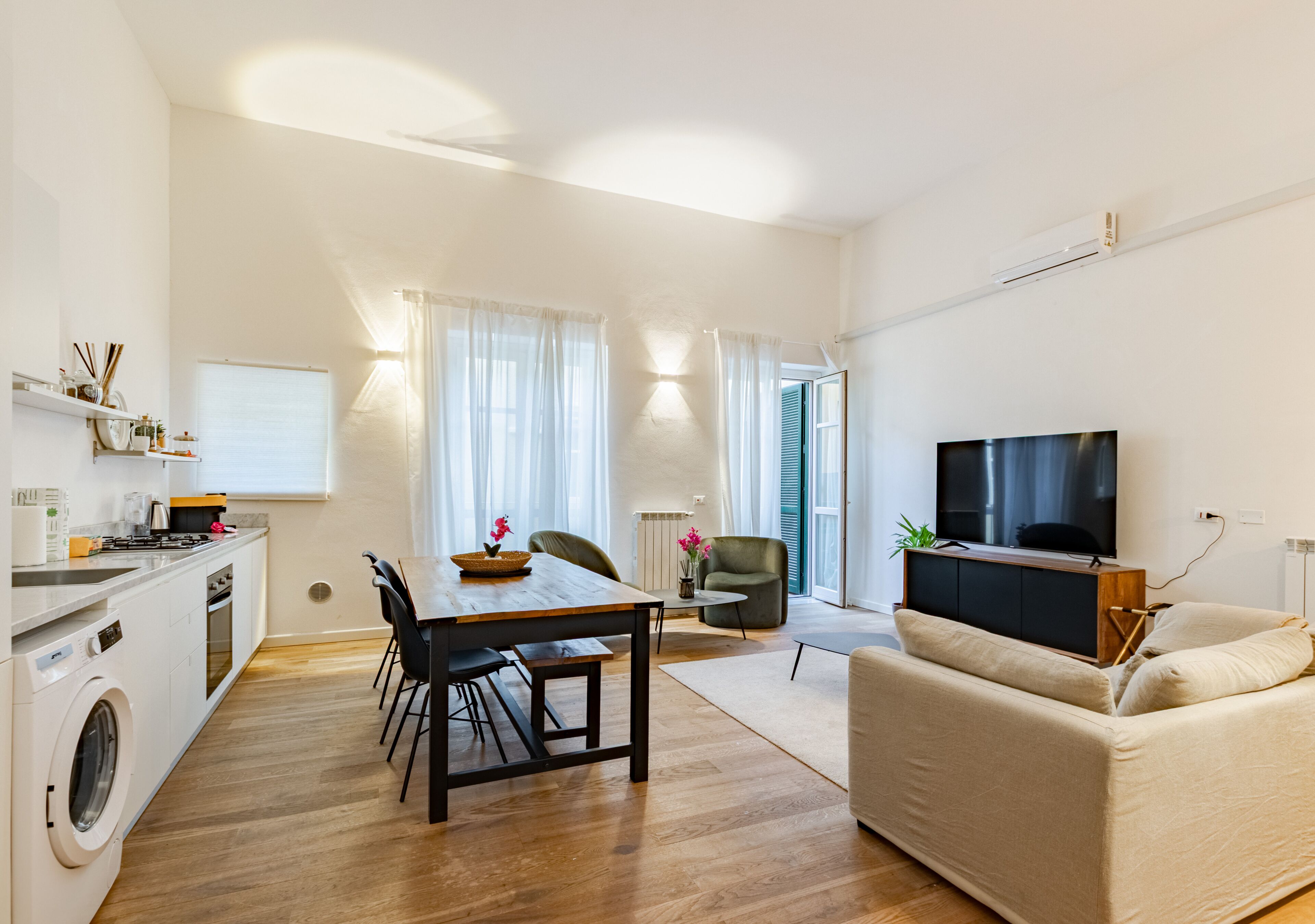 A modern apartment with a kitchen, dining area, living room, and a TV.