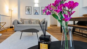 A modern living room with a sofa, a coffee table, a vase with flowers, and a decorative candle holder.