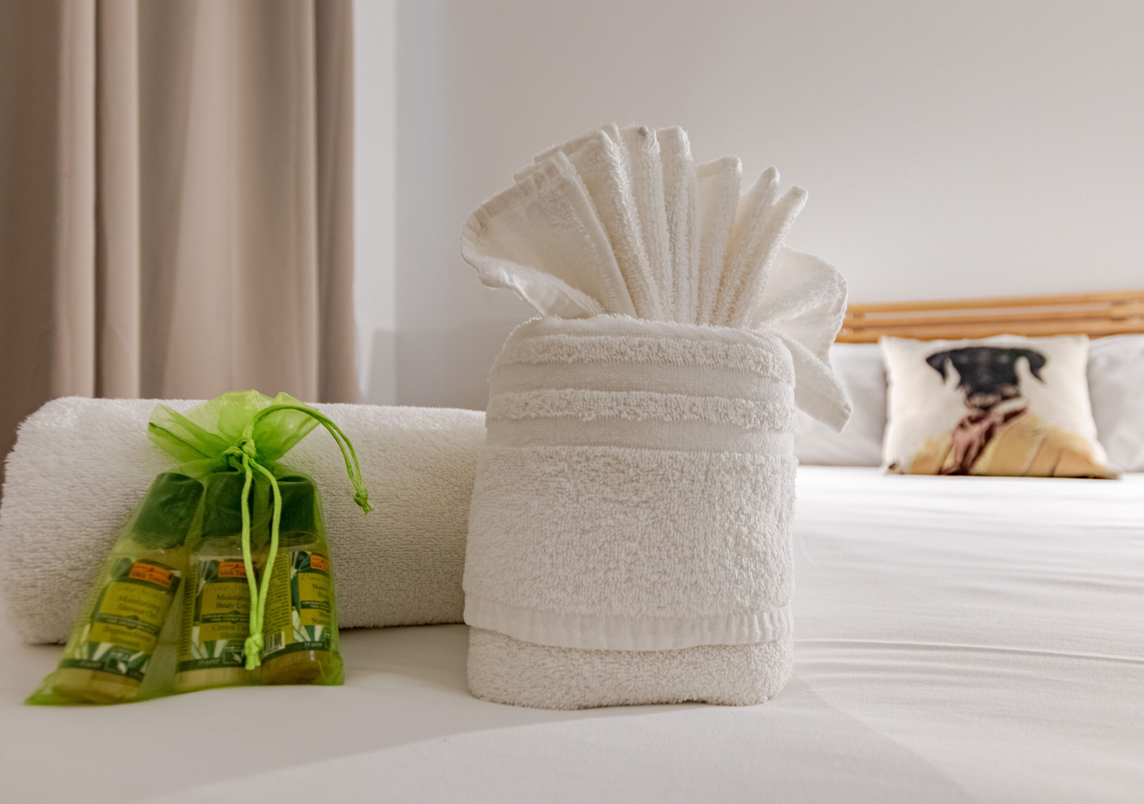 Een net opgemaakt bed met een witte handdoek en een klein cadeautje.