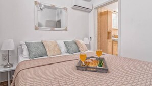 Une chambre à coucher bien rangée, avec un lit, des lampes de chevet, un plateau contenant des articles pour le petit-déjeuner et un miroir au mur.