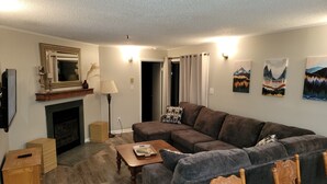 Una sala de estar con chimenea, un sofá, una mesa de centro y un televisor.