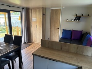 A modern interior with a wooden dining table, chairs, a sofa with cushions, and a wooden cabinet.