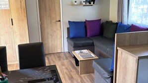 Una sala de estar moderna con un sofá, sillas, una mesa de centro y un mueble de madera.