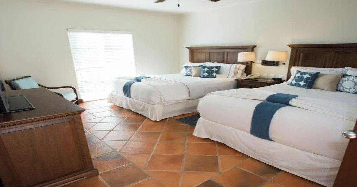 Una habitación de hotel con dos camas, un escritorio y una ventana.