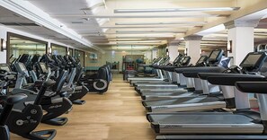 A gym with multiple treadmills and elliptical machines arranged in rows.